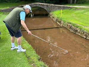 Gordon Wood retrieves his ball from the stream